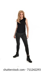 full length portrait of blonde girl wearing black clothes and boots. standing pose on white background.