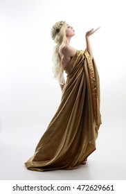 full length portrait of a blonde woman wearing a long gold draped grecian style gown. isolated on white background.