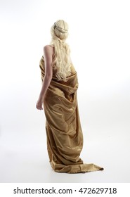 full length portrait of a blonde woman wearing a long gold draped grecian style gown. isolated on white background.