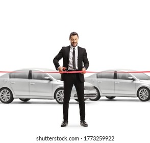 Full length portrait of a businessman cutting a red ribbon tape in a car showroom isolated on white background - Shutterstock ID 1773259922