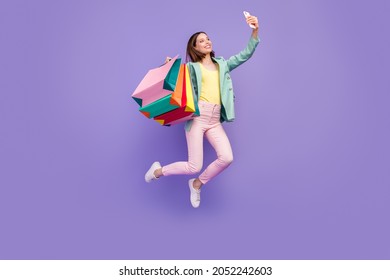 Full length portrait of carefree excited girl take selfie hold store mall packages isolated on violet color background