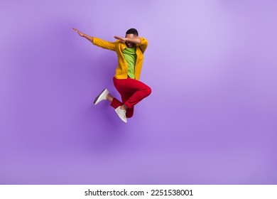 Full length portrait of carefree overjoyed person jumping arms dabbing isolated on purple color background