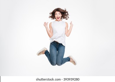 Full length portrait of a cheerful cute woman jumping isolated on a white background