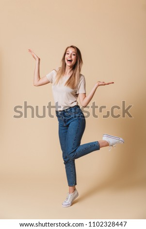 Full length portrait of cheerful woman 20s wearing casual clothing rejoicing and raising up arms isolated over beige background