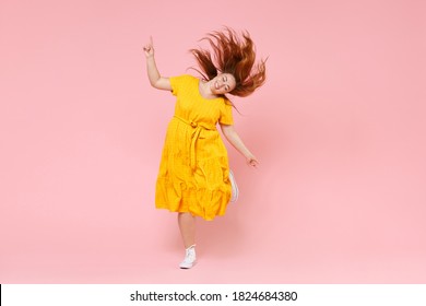 Full Length Portrait Cheerful Young Redhead Plus Size Body Positive Chubby Overweight Woman In Yellow Dress Posing Jumping Dancing With Fluttering Hair Isolated On Pastel Pink Color Background Studio