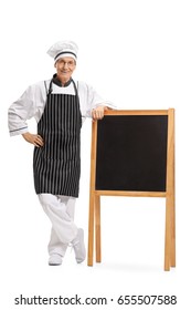 Full Length Portrait Of A Chef Standing By A Blank Blackboard Isolated On White Background