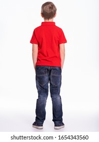 Full length portrait of a child standing back to the camera. Kid stands at studio, rear view.  Little boy dressed in red t-shirt and jeans, posing at studio, Back view 