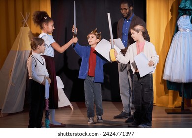 Full length portrait of children rehearsing school play on stage in theater with little boy prince reciting lines - Powered by Shutterstock