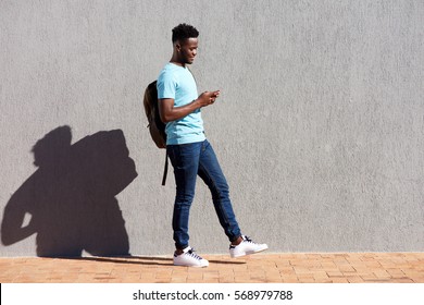 Full Length Portrait Of College Student Walking With Bag And Mobile Phone