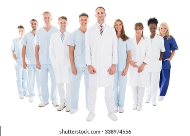 Full Length Portrait Of Confident Doctor Standing With His Team Against White Background