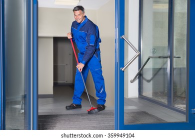 Full length portrait of confident mature worker with broom cleaning floor - Shutterstock ID 359949104