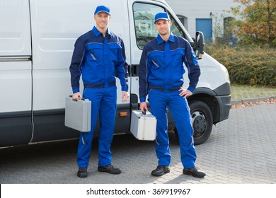 Full length portrait of confident technicians standing against truck on street