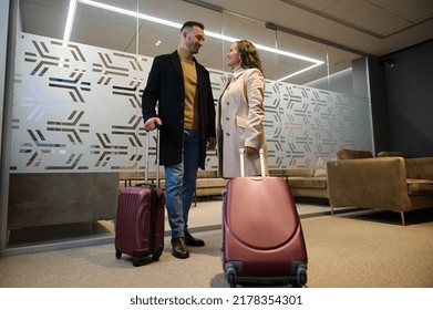 Full Length Portrait Of Couple, Pretty Woman And Handsome Man With Suitcases Traveling Together, Waiting To Board A Flight In Airport VIP Lounge. Business Trip, Team Of Colleagues, Human Relationships