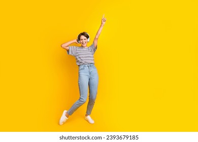 Full length portrait of crazy person touch headphones point finger rejoice empty space isolated on yellow color background - Shutterstock ID 2393679185