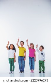 Full length portrait of cute little kids in casual clothes looking and pointing up, isolated on a white background - Shutterstock ID 2223996273