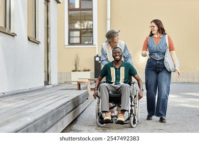 Full length portrait of diverse group of friends with smiling African American man with disability moving towards camera in city setting with sunlight copy space - Powered by Shutterstock