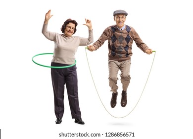 Full length portrait of an elderly woman with a hula hoop and a senior man jumping with a skipping rope isolated on white background