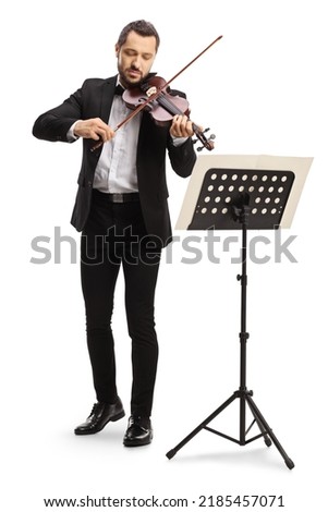 Full length portrait of an elegant man playing a violin with a music stand isolated on white background 