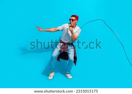 Full length portrait of excited crazy person hold wired microphone sing tie front shirt isolated on blue color background