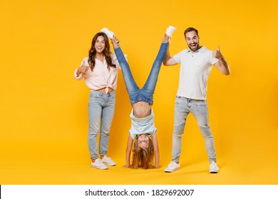 Vollständiges Portrait begeisterte junge Eltern Mama Papa mit Kind Tochter Mädchen in T-Shirts zeigen Daumen auf Kopf einzeln auf gelbem Hintergrund Studioaufnahme. Familienzeitkonzept