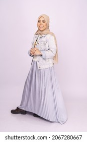 Full Length Portrait Of Fashionable Young Woman In Maxi Skirt, Long Sleeves Jacket And Hijab Isolated Over White Background. Stylish Muslim Female Hijab Fashion Lifestyle Portraiture Concept.