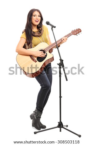 Full length portrait of a female signer playing on acoustic guitar and singing on a microphone isolated on white background