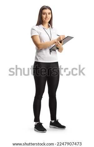 Full length portrait of a female sport coach holding a clipboard and smiling at camera isolated on white background

