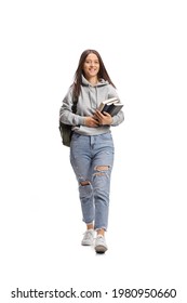 Full length portrait of a female student carrying books and walking towards camera isolated on white background