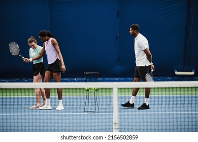 Full length portrait of female tennis coach working with young African American woman during practice at indoor court - Powered by Shutterstock