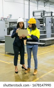 Full Length Portrait Of Focused Women Looking At Laptop At Plant. Two Female Employees Talking While Standing At Factory With Laptop. Print Manufacturing Concept