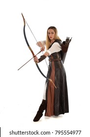 full length portrait of girl wearing brown  fantasy costume, holding a bow and arrow. standing pose on white studio background. 
