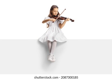 Full length portrait of a girl in a white dress sitting on a blank panel and playing a violin isolated on white background 