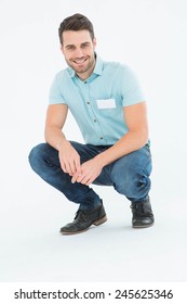 Full length portrait of handsome delivery man crouching on white background