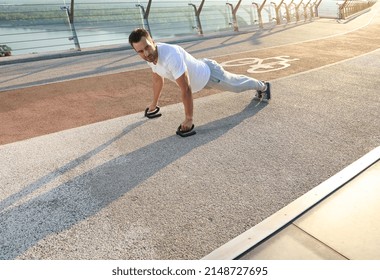 Full Length Portrait Of A Handsome Middle Aged Caucasian Man, Muscular Build Athlete Doing Push Ups During An Outdoor Workout On The City Bridge Early In The Morning