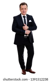 Full Length Portrait Of Handsome Senior Man 55-65 Years Old. Smart Businessman With Crossed Hands. Male In Black Suit With Black Tie And White Shirt. Isolated On White Background