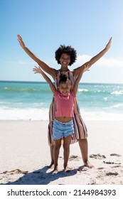 Full Length Portrait Of Happy African American Mother And Daughter With Arms Raised At Beach. Unaltered, Family, Lifestyle, Togetherness, Enjoyment And Holiday Concept.