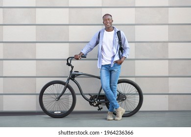 Full Length Portrait Of Happy Black Guy With Modern Bike Standing On City Street And Looking At Camera. Millennial African American Man With Modern Bicycle On Ride Near Brick Wall Outside