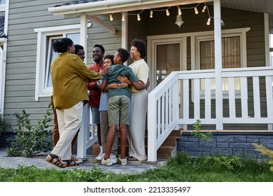 Full Length Portrait Of Happy Black Family Embracing While Standing On Porch Of New House, Copy Space