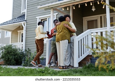 Full Length Portrait Of Happy Black Family Embracing On Porch Of New House, Copy Space