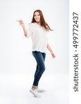Full length portrait of a happy casual woman pointing finger away isolated on a white background