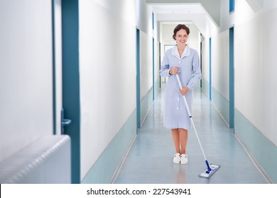 Full Length Portrait Of Happy Cleaner Mopping Floor In Hospital