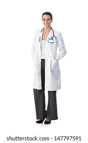 Full length portrait of happy female doctor standing in smock smiling at camera, cutout on white.