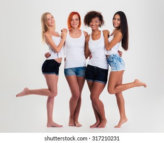 Full Length Portrait Of A Happy Four Multi Ethnic Women Standing Isolated On A White Background And Looking At Camera