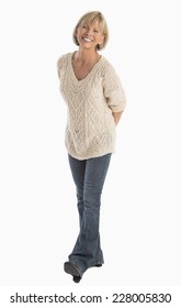 Full Length Portrait Of Happy Mature Woman With Hands Behind Back Walking Over White Background