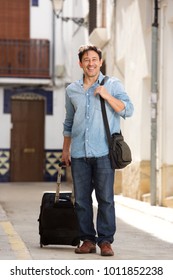 Full Length Portrait Of Happy Older Man Walking With Luggage On The Street