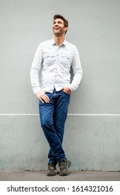 Full Length Portrait Of Happy Older Man Leaning Against Wall And Looking Up