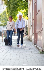 Full Length Portrait Happy Older Couple Walking With Suitcase On Street