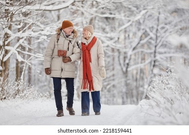 Full length portrait of happy senior couple enjoying walk in winter forest and looking at each other with love, copy space - Shutterstock ID 2218159441