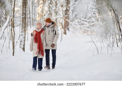 Full length portrait of happy senior couple enjoying walk in winter forest and looking at each other, copy space - Powered by Shutterstock