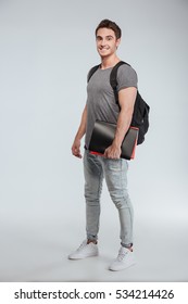 Full Length Portrait Of A Happy Smiling Student Standing With Backpack And Folders Over White Background